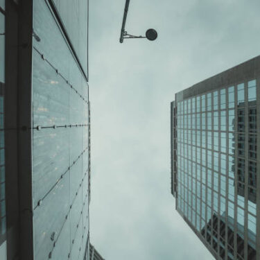 Low-angle close-up shot of skyscrapers in Hong Kong, reaching towards an overcast sky.  The city's architecture dominates the frame, emphasizing height and density.
